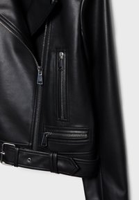 Sort motorcykeljakke i læder med flere lynlåse, et bæltet talje og tekstureret stof med glatte accenter og detaljerede syninger.