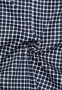 Tessuto blu navy e bianco con un motivo floreale ripetuto, caratterizzato da motivi circolari e piccoli punti di connessione, con una texture liscia.