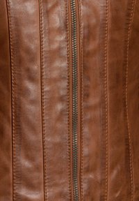 Tessuto in pelle marrone con cuciture verticali e una zip metallica al centro, che evidenzia una texture liscia e un colore ricco.