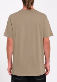 Camiseta de algodón color caqui con mangas cortas, cuello redondo y un ajuste relajado. Textura suave, diseño minimalista, sin gráficos ni adornos en la parte posterior.