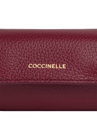 Portafoglio in pelle a grana rossa scura con logo "COCCINELLE" dorato impresso sul risvolto anteriore.