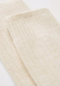 Crème kleurige gebreide sokken met een geribbelde textuur, voorzien van een zachte, geweven stof en een naadloos ontwerp.