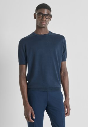 Maglione corto a maniche corte di colore blu navy con scollatura rotonda e orlo a costine. Realizzato in un tessuto liscio, indossato con pantaloni abbinati.