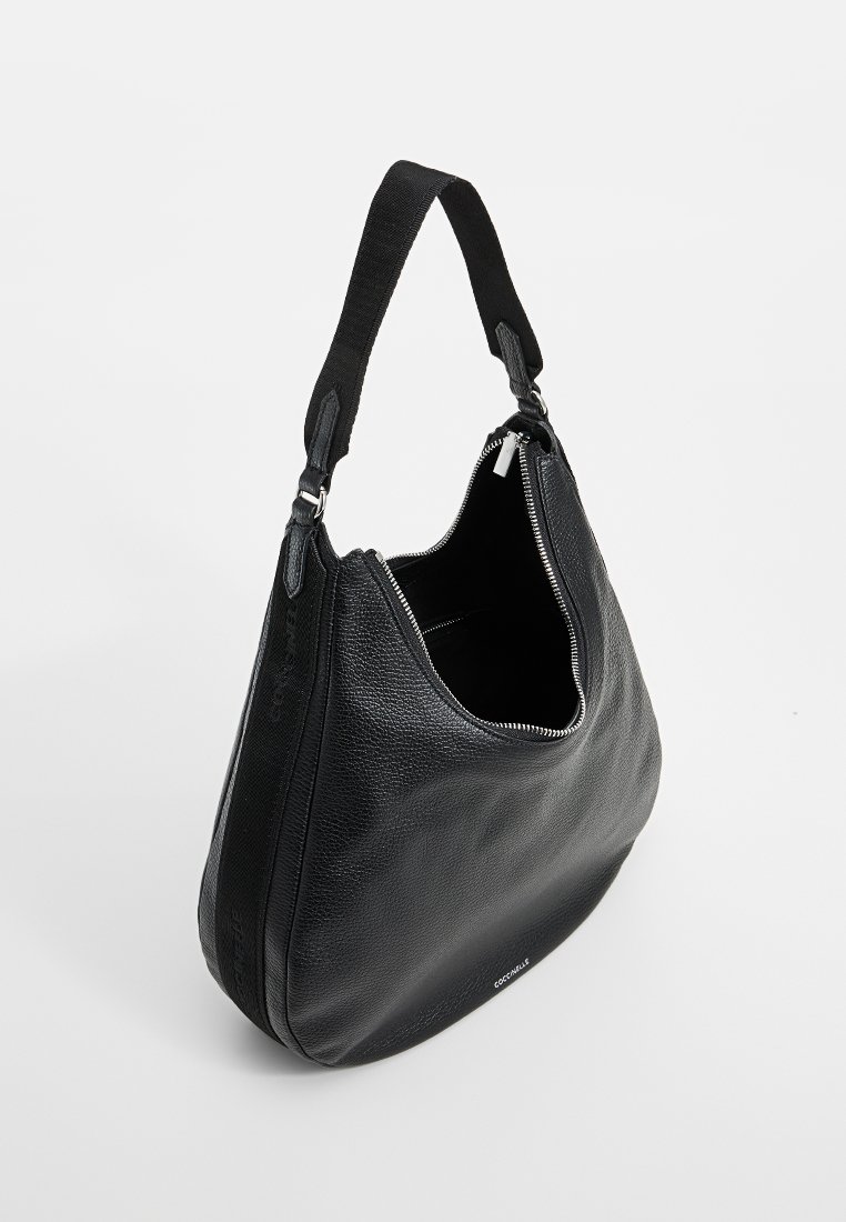 Sac hobo en cuir noir avec une texture mouchetée, design surdimensionné et bandoulière en tissu contrasté. Il possède une fermeture zippée sur le dessus et un branding discret.