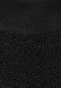 Tessuto nero con texture, dall'aspetto morbido e peloso, caratterizzato da una parte superiore liscia e una parte inferiore ruvida, entrambi in profondi toni di nero.