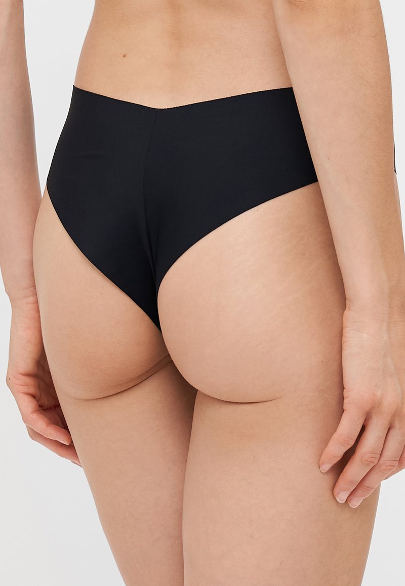 Slip bikini nero a vita alta realizzato in un tessuto morbido, con un design minimalista e uno scollo posteriore basso. Esalta la forma naturale.