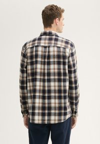 Herren-Langarm-Flanellhemd in marineblau, braun und weißem Karo. Verfügt über einen spitzen Kragen und Knopfmanschetten, mit einem Rückenpasse-Detail.