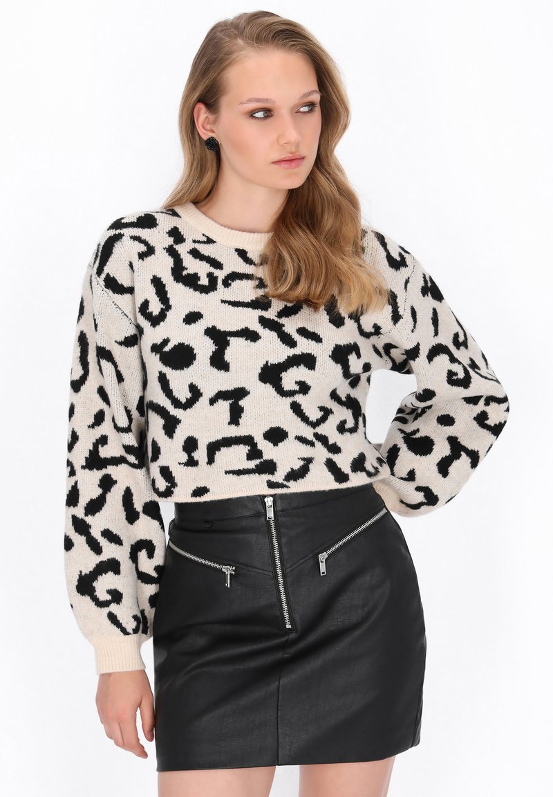Strikket beige sweater med sort abstrakt leopardprint, cropped design og lange ærmer. Sort læder mini-nederdel med lynlåselementer.