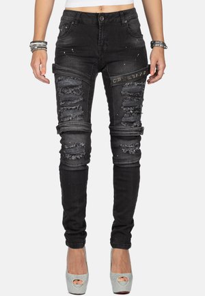 Schwarze skinny Jeans aus Denim, mit aufgerissenen Akzenten, verwaschenen Details und einem kleinen Logo-Patch am Oberschenkel.