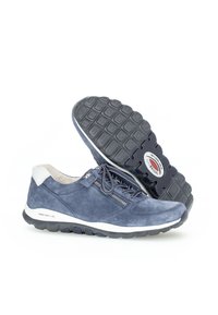 Dunkelblaue Wildledersneaker mit einem weißen Absatzakzent, strukturiertem Sohlen und einem seitlichen Reißverschlussdetail. Leicht und für Komfort ausgelegt.