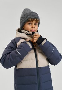 Padded zimowa kurtka w granatowym i beżowym kolorze, z zamkiem błyskawicznym, wysokim kołnierzem i ściągaczami przy rękawach. W komplecie szara, dziana czapka.