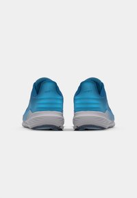 Des chaussures de sport bleues présentent une tige lisse, une forme arrondie, des semelles rembourrées et une adhérence texturée sur la semelle extérieure.