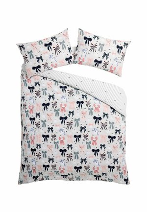 Funda de edredón y fundas de almohada con patrones de lazos multicolores sobre un fondo blanco, una esquina muestra el reverso a rayas.