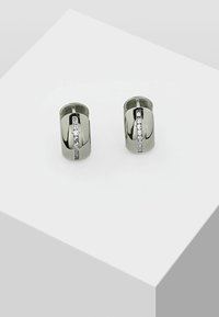 Orecchini a cerchio argentati con una finitura lucida, caratterizzati da una fila verticale di cristalli trasparenti per un tocco di dettaglio in più.