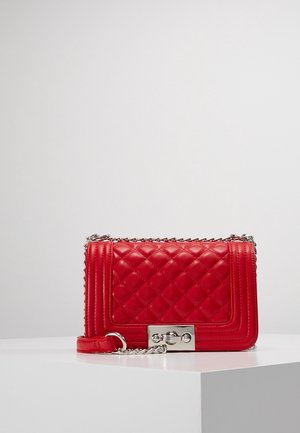 Red quilted leather crossbody bag with silver chain strap and rectangular silver turn-lock clasp on white surface.