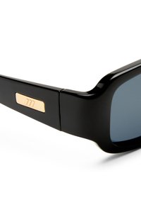 Μαύρα ορθογώνια γυαλιά ηλίου με σκοτεινούς φακούς και χρυσή μεταλλική πλακέτα με λογότυπο στο μπράτσο του βραχίονα, τοποθετημένα σε λευκό φόντο.