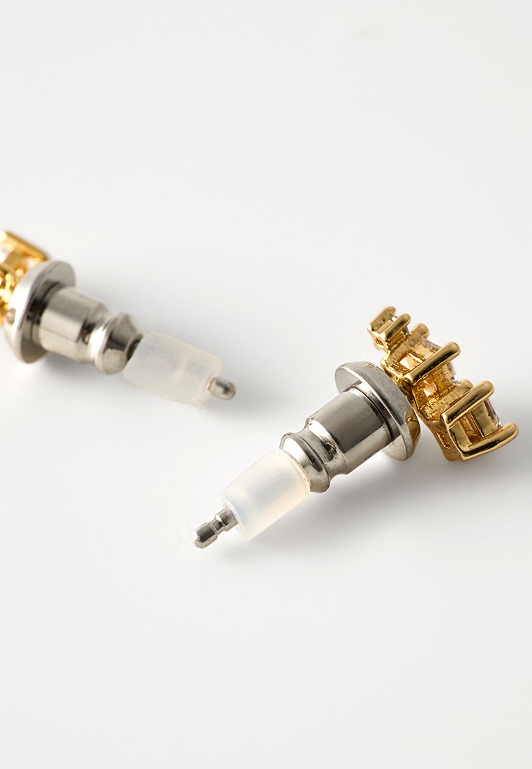Gold- und Silberohrstecker mit einer klaren Kunststoffrückseite und filigranem Design, verziert mit goldenen Akzenten und einem metallischen Finish.