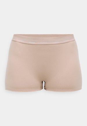 Beige cykelskorts lavet af elastisk stof med en glat overflade, med et smalt taljebånd mærket "GUESS." Shortsene har en tætsiddende pasform.
