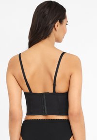 Black underbust corset made from smooth fabric, featuring thin adjustable straps, a hook-and-eye closure, and a structured design.