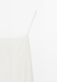 Weißes Kleid mit dünnen Spaghetti-Trägern, das über eine weiche Textur und einen geraden Schnitt verfügt. Eine auffällige Nahtdetail läuft vertikal entlang der Vorderseite.