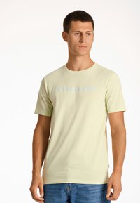 Camiseta de algodón verde claro con cuello redondo y mangas cortas. "COPENHAGUE LINDENBERGH" impreso en azul pálido en el pecho.