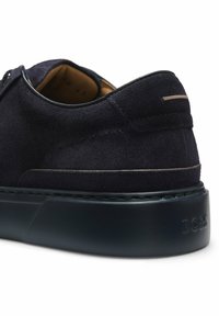 Baskets en daim bleu marine foncé avec semelle noire épaisse et détail de couture subtil, vues arrière et latérale.