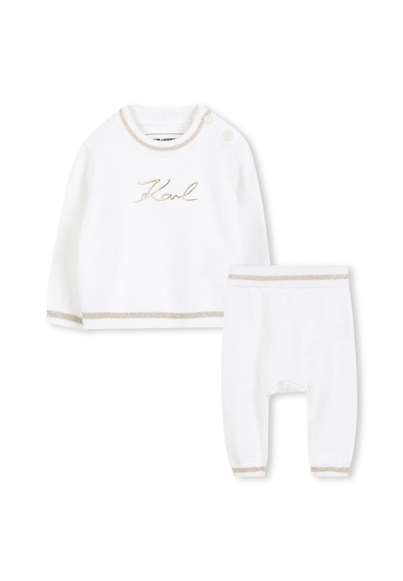 Witte gebreide outfit bestaande uit een longsleeve top met gouden borduursels en crème accenten, gecombineerd met bijpassende broek met elastische manchetten.