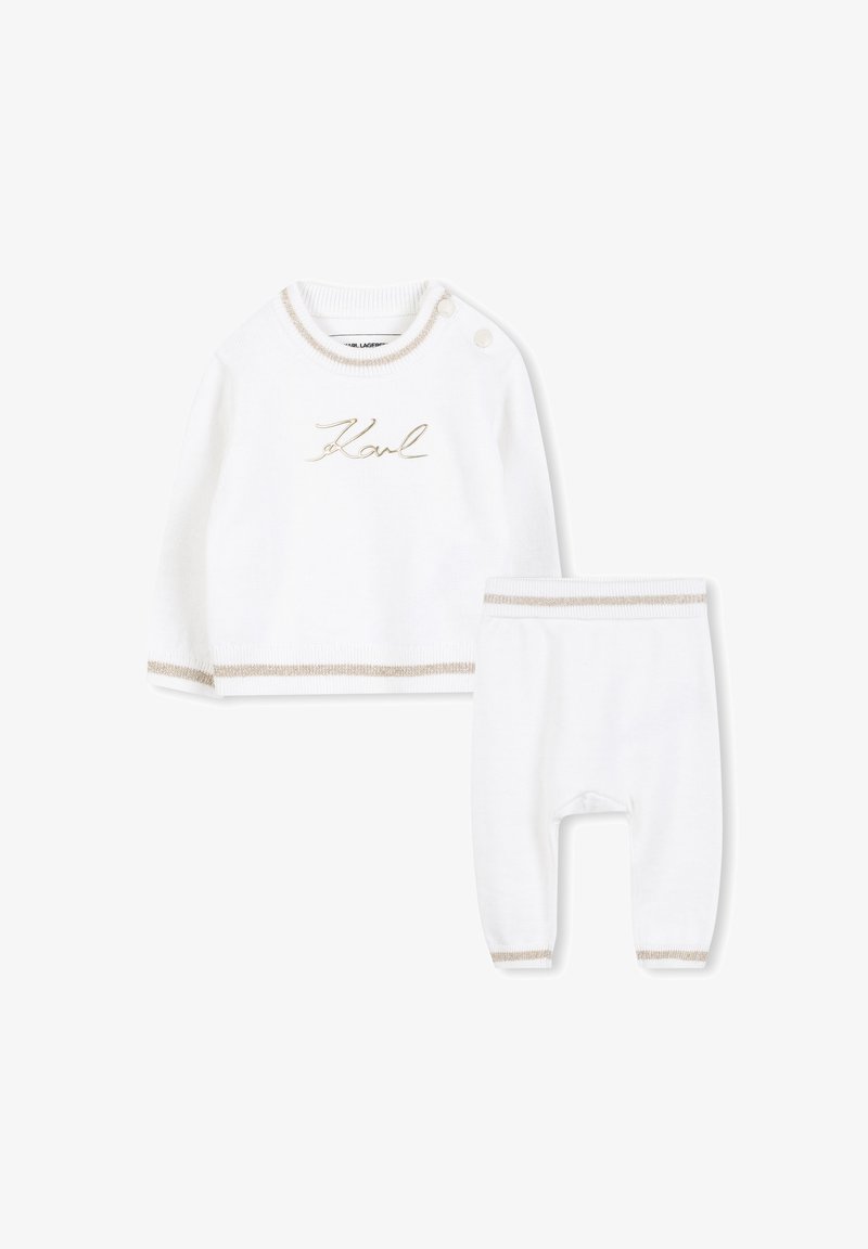 Ensemble en tricot blanc composé d'un haut à manches longues avec broderies dorées et accents crème, associé à un pantalon assorti avec des poignets élastiques.