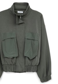 Giacca verde oliva con colletto alto, orlo arricciato e due tasche anteriori con pattina. Realizzata in un materiale leggero e liscio.