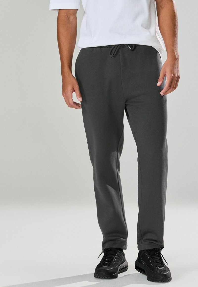 Grijze sweatpants van zacht materiaal, met een elastische tailleband met een trekkoord, taps toelopende benen en zijzakken voor extra gemak.
