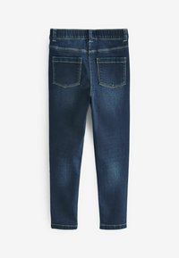 Jeans in denim blu scuro con un elastico in vita, cinque tasche e una leggera scoloritura sulle gambe. I punti di cucitura sono a contrasto e ben definiti.