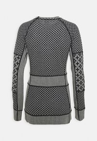 Svart og hvit mønstret genser med tettsittende design, med ribbestrikkede mansjetter og nederkant, samt varierende teksturer og geometriske motiver.
