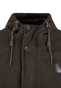 Braune Jacke mit Kapuze, zwei Knöpfen und Kordelzügen. Weicher schwarzer Innenfutter mit einer strukturierten Außenschicht und einem kreisförmigen Logodetail.