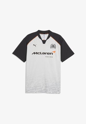 Maillot McLaren Racing à manches courtes blanc et noir avec logo Puma, manches noires, accents orange et motif géométrique subtil en bas.