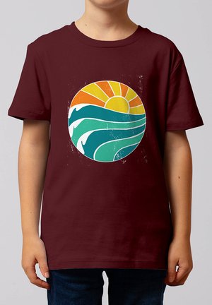 Enfant portant un t-shirt bordeaux avec un graphique coloré de soleil et de vague océanique sur la poitrine.