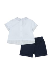 Camisa blanca de manga corta con cuello y puños a rayas, combinada con pantalones cortos azul marino con cintura elástica.