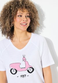 Camiseta blanca con escote en V, que presenta un gráfico de un scooter rosa y acentos en negro. Tejido suave y ligero con mangas raglán.