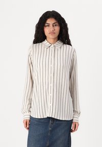 Camicia color crema con righe verticali blu, maniche lunghe e colletto classico. Tessuto morbido e leggera lucentezza.