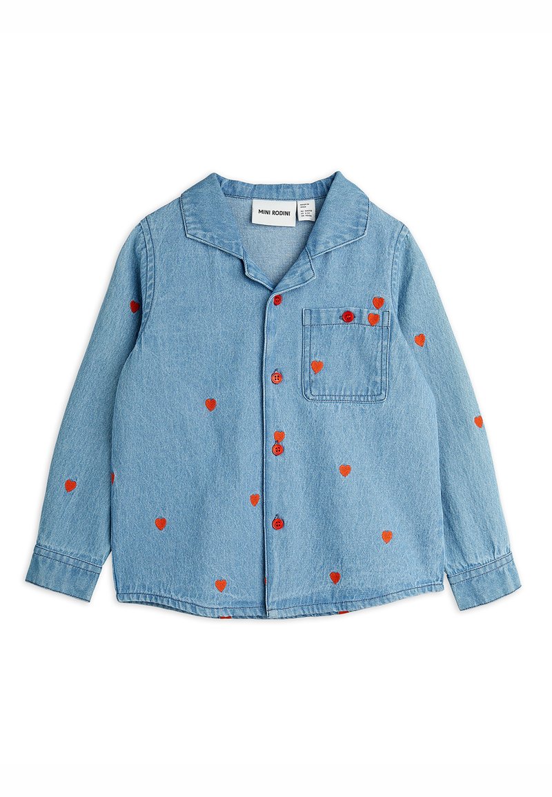 Camisa de denim azul clara com mangas longas, padrões de corações vermelhos e botões vermelhos combinantes. Apresenta um colarinho tipo notch e um bolso no peito.
