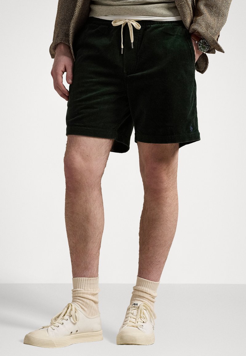 Shorts verzi din catifea cu un brâu elastic și șnur crem. Asortați cu adidași și șosete de un crem deschis. Design simplu, fără modele.