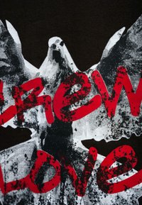 Zwarte t-shirt met een graphic van rode gestileerde tekst boven een ontwerp van een witte en grijze vogel, met verouderde texturen en patronen.