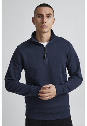Marineblaues Sweatshirt mit Reißverschlusskragen, langen Ärmeln, gerippten Bündchen und Saum, aus weichem Material gefertigt, ohne sichtbare Muster oder Akzente.