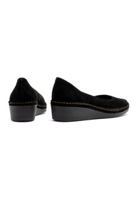 Scarpe con zeppa in camoscio nero, con punta arrotondata e leggera apertura, caratterizzate da dettagli di cucitura in contrasto e una solida base in legno.