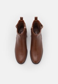 Brown leather ankle boots with zip closure, round toe, and pull tabs at the back. Smooth texture with minimal detailing and a black sole.