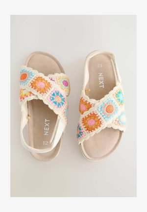 Šķērsoti sandales ar daudzu krāsu ziedu rakstiem. Mīksti, gaišas krāsas siksniņas virs bēša pamatnes. Izmērs 12.