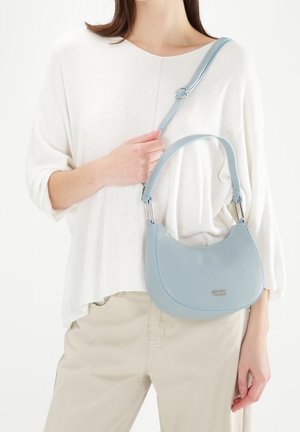 Světlomodrá kožená taška s zakřiveným tvarem a nastavitelným popruhem. Má hladkou texturu a jemný kovový detail loga.