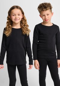 Schwarze Langarmoberteile und Leggings aus einem weichen, dehnbaren Stoff. Das Mädchen trägt einen locker sitzenden Schnitt; das Oberteil des Jungen ist körpernah mit Rundhals.