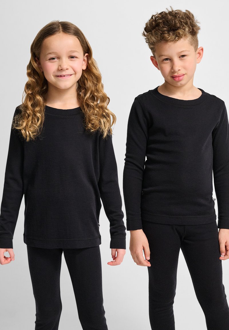 Schwarze Langarmoberteile und Leggings aus einem weichen, dehnbaren Stoff. Das Mädchen trägt einen locker sitzenden Schnitt; das Oberteil des Jungen ist körpernah mit Rundhals.