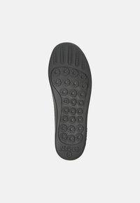 Semelle de chaussure en caoutchouc noir présentant plusieurs motifs de grip circulaires, des rainures horizontales et un logo en relief. Taille indiquée comme 42.