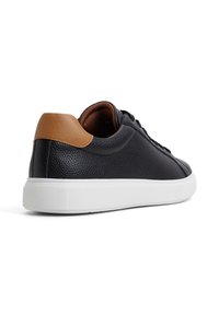 Sneaker in pelle nera con finitura testurizzata, dettaglio marrone chiaro sul tallone, suola in gomma bianca e design con lacci.